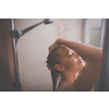 Young woman washing her hair with shampoo, taking a hot long shower