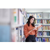 Reading a book in library. Young attractive librarian reading a book between library bookshelves