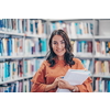 Reading a book in library. Young attractive librarian reading a book between library bookshelves