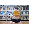 Woman student taking notes from a book at library. Young woman sitting and doing assignments in college library.