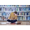 Woman student taking notes from a book at library. Young woman sitting and doing assignments in college library.