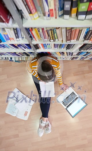 student taking notes from a book at library. Young woman sittingin in school library and working with laptop student taking notes from a book at library. Young woman sittingin in school library and working with laptop
