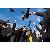 Congratulations! Low angle view of happy group of six young cheerful graduates in black gowns, throwing up their head wear in the air and celebrating, in blue summer sky, laughing, enjoying