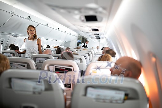Pretty, young woman aboard an airplane during a lang haul commercial flight - stretching her legs a bit, walking in the aisle Pretty, young woman aboard an airplane during a lang haul commercial flight - stretching her legs a bit, walking in the aisle