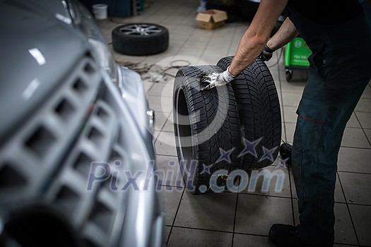 Car mechanic changind tires of a car in a repair shop/car garage (shallow DOF/color toned image) Car mechanic changind tires of a car in a repair shop/car garage (shallow DOF/color toned image)
