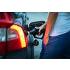 Young female driver refueling her car at night with gas(color toned image; shallow DOF)