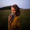 Beautiful young woman outdoors with a bouquet of wild flowers in a field, enjoying nature. Happy Woman on spring meadow