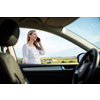 Pretty midle aged woman at the steering wheel of her car, having a break on a long trip, making a phone call