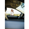 Pretty midle aged woman at the steering wheel of her car, having a break on a long trip, making a phone call