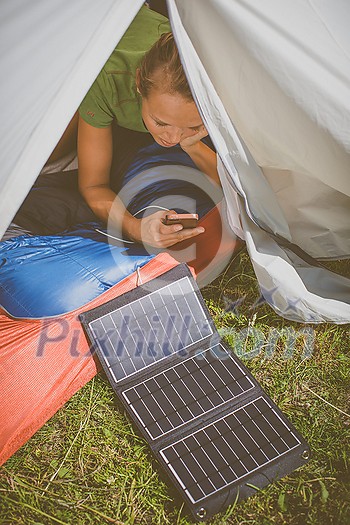 Cell phone charging with a solar charger in a tent during an outdoor trip Cell phone charging with a solar charger in a tent during an outdoor trip