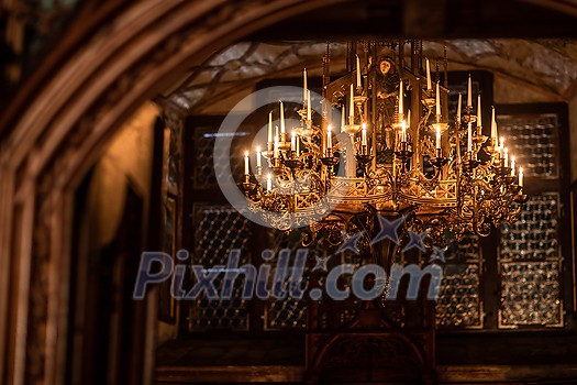 Splendid chandelier with lit candles in a beautiful room of an old mansion Splendid chandelier with lit candles in a beautiful room of an old mansion