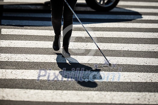 Blind woman walking on city streets, using her white cane to navigate the urban space better and to get to her destination safely Blind woman walking on city streets, using her white cane to navigate the urban space better and to get to her destination safely