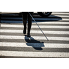 Blind woman walking on city streets, using her white cane to navigate the urban space better and to get to her destination safely