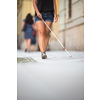 Blind woman walking on city streets, using her white cane to navigate the urban space better and to get to her destination safely