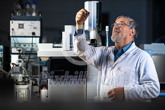 Senior scientist in a chemistry lab carrying out research - looking at gas chromatography samples, preparing the analysis on a modern gas chromatographer (color toned image) Senior scientist in a chemistry lab carrying out research - looking at gas chromatography samples, preparing the analysis on a modern gas chromatographer (color toned image)