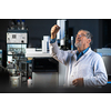 Senior scientist in a chemistry lab carrying out research - looking at gas chromatography samples, preparing the analysis on a modern gas chromatographer (color toned image)