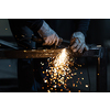 Man working on iron with grinder. Man at work. Sparkles and fire from grinder cutting. Grinder. Worker.