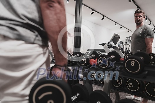 Struggling with age. Confident senior man exercising with dumbbells in the health club. Selective focus. High-quality photo Struggling with age. Confident senior man exercising with dumbbells in the health club. Selective focus. High-quality photo