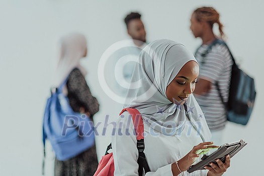 African female student with a group of friends in the background wearing traditional Islamic hijab clothes. Selective focus. High-quality photo African female student with a group of friends in the background wearing traditional Islamic hijab clothes. Selective focus. High-quality photo