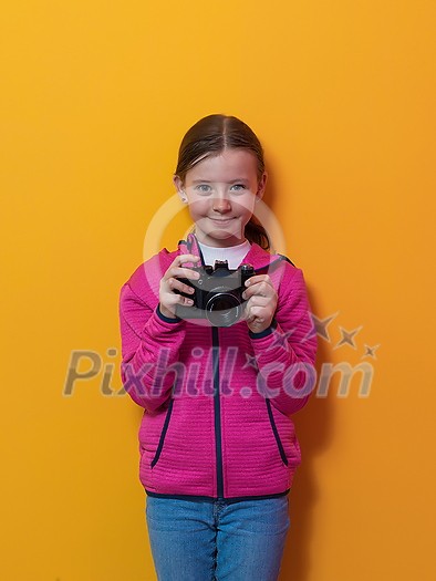 Little girl photographer isolated on yellow background smiling taking photos with a retro vintage camera. High quality photo Little girl photographer isolated on yellow background smiling taking photos with a retro vintage camera. High quality photo