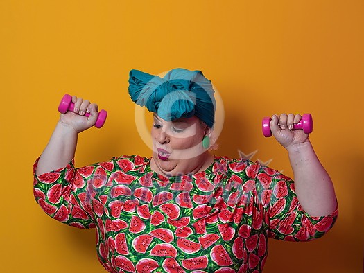 Fat woman dieting, fitness and health at home.Big woman and sport. Healthy, fitness and sports concept. Plus size young woman doing exercise with dumbbells on yellow background. High quality photo Fat woman dieting, fitness and health at home.Big woman and sport. Healthy, fitness and sports concept. Plus size young woman doing exercise with dumbbells on yellow background. High quality photo