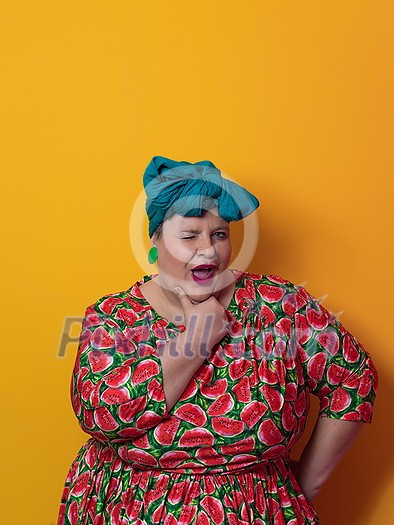 Funny plus size sexy model woman with trendy makeup, fashionable overweight blonde in colorful dress posing at the yellow background in studio. High quality photo Funny plus size sexy model woman with trendy makeup, fashionable overweight blonde in colorful dress posing at the yellow background in studio. High quality photo