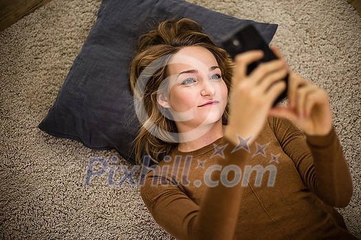 Pretty, young woman using her smart phone at home Pretty, young woman using her smart phone at home