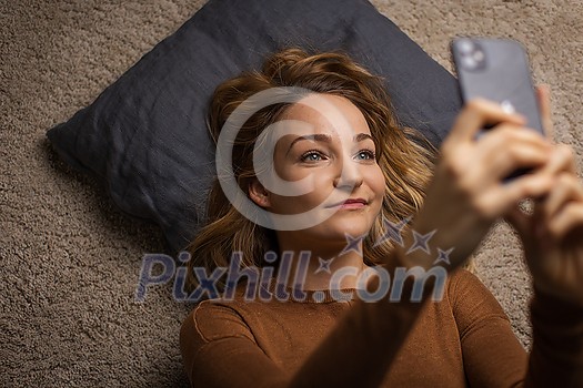 Pretty, young woman using her smart phone at home Pretty, young woman using her smart phone at home