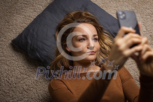 Pretty, young woman using her smart phone at home Pretty, young woman using her smart phone at home