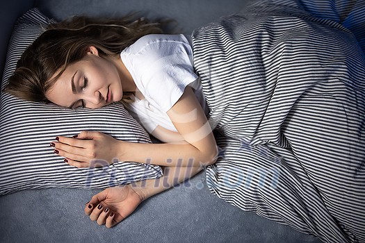 Pretty, young woman sleeping in her bed late in the morning on a weekend - compensating for the lack of sleep Pretty, young woman sleeping in her bed late in the morning on a weekend - compensating for the lack of sleep