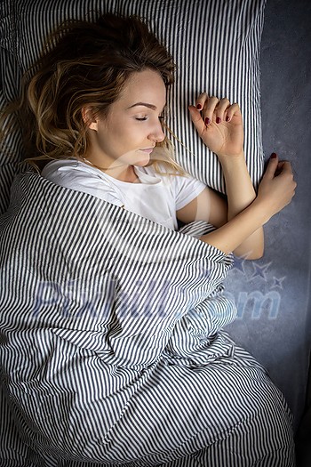 Pretty, young woman sleeping in her bed late in the morning on a weekend - compensating for the lack of sleep Pretty, young woman sleeping in her bed late in the morning on a weekend - compensating for the lack of sleep