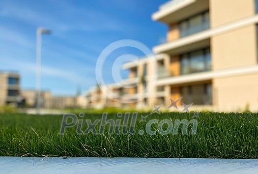 Modern and new apartment building. Multistoried modern, new and stylish living block of flats. Selective DOF, focus on the grass with blurred buildings in the background (ample copy space) Modern and new apartment building. Multistoried modern, new and stylish living block of flats. Selective DOF, focus on the grass with blurred buildings in the background (ample copy space)