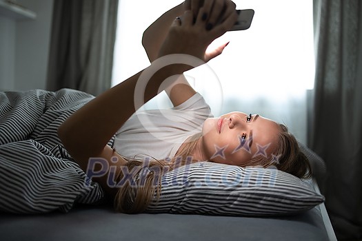 Pretty, young woman sleeping in her bed with her cell phone close to her. Smartphone in Bed Mobile/smartphone Addiction Concept. Pretty, young woman sleeping in her bed with her cell phone close to her. Smartphone in Bed Mobile/smartphone Addiction Concept.