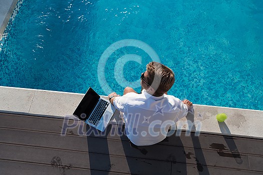 A modern elderly man enjoys the pool while working on his laptop next to a modern luxury house. Selective focus. High-quality photo A modern elderly man enjoys the pool while working on his laptop next to a modern luxury house. Selective focus. High-quality photo