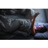 Middle-aged woman using her tablet computer before sleep in bed in the evening - exposure to blue light right before sleep