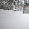 Car on a snowy winter road amid forests - using its four wheel drive capacities to get through the snow