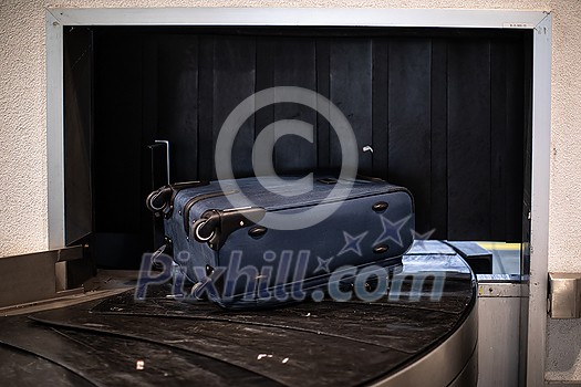 Arrived luggage going around on a conveyor belt waiting to be claimed at the baggage claim zone at a modern international airport Arrived luggage going around on a conveyor belt waiting to be claimed at the baggage claim zone at a modern international airport