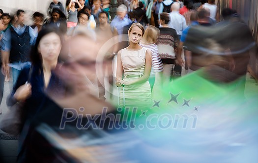 Crowd of people walking on city street - motion blurred image with unrecognizable faces - Young woman standing still, feeling down, depressed Crowd of people walking on city street - motion blurred image with unrecognizable faces - Young woman standing still, feeling down, depressed