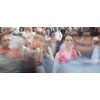 Crowd of people walking on city street - motion blurred image with unrecognizable faces - Young woman standing still, feeling down, depressed