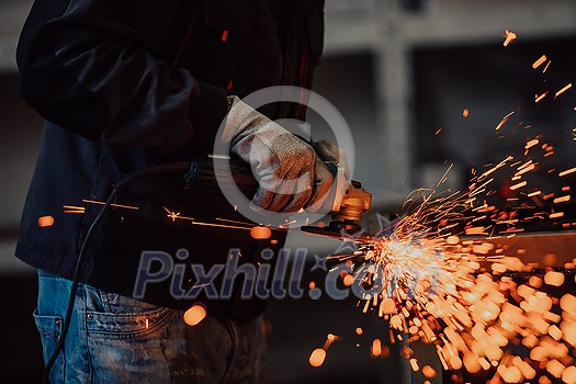 Heavy Industry Engineering Factory Interior with Industrial Worker Using Angle Grinder and Cutting a Metal Tube. Contractor in Safety Uniform and Hard Hat Manufacturing Metal Structures. High-quality photo