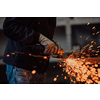 Heavy Industry Engineering Factory Interior with Industrial Worker Using Angle Grinder and Cutting a Metal Tube. Contractor in Safety Uniform and Hard Hat Manufacturing Metal Structures. High-quality photo