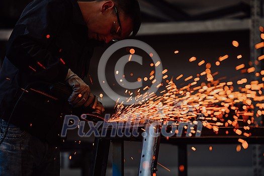 Heavy Industry Engineering Factory Interior with Industrial Worker Using Angle Grinder and Cutting a Metal Tube. Contractor in Safety Uniform and Hard Hat Manufacturing Metal Structures. High-quality photo Heavy Industry Engineering Factory Interior with Industrial Worker Using Angle Grinder and Cutting a Metal Tube. Contractor in Safety Uniform and Hard Hat Manufacturing Metal Structures. High-quality photo