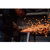 Heavy Industry Engineering Factory Interior with Industrial Worker Using Angle Grinder and Cutting a Metal Tube. Contractor in Safety Uniform and Hard Hat Manufacturing Metal Structures. High-quality photo