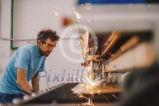 Within heavy industry. A man works in a modern factory on a CNC machine. Selective focus. High-quality photo Within heavy industry. A man works in a modern factory on a CNC machine. Selective focus. High-quality photo