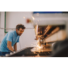 Within heavy industry. A man works in a modern factory on a CNC machine. Selective focus. High-quality photo