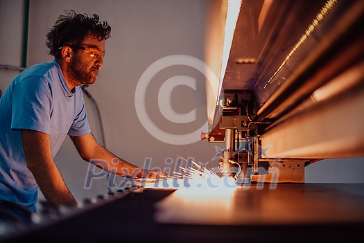 Within heavy industry. A man works in a modern factory on a CNC machine. Selective focus. High-quality photo Within heavy industry. A man works in a modern factory on a CNC machine. Selective focus. High-quality photo