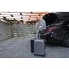 A photo of a suitcase standing next to a car in a luxury garage. High-quality photo