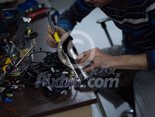 Industrial worker man soldering cables of manufacturing equipment in a factory. Selective focus. High quality photo