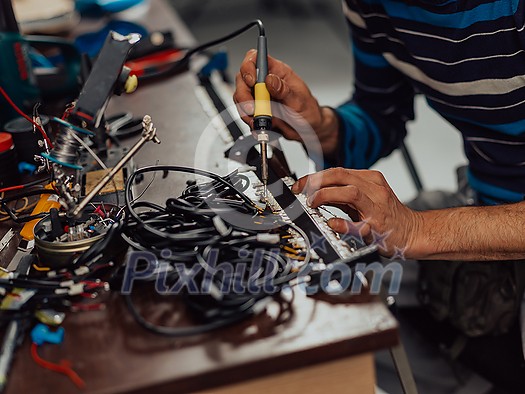 Industrial worker man soldering cables of manufacturing equipment in a factory. Selective focus. High-quality photo