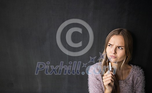 Pretty, young female student in front of a blackboard during class